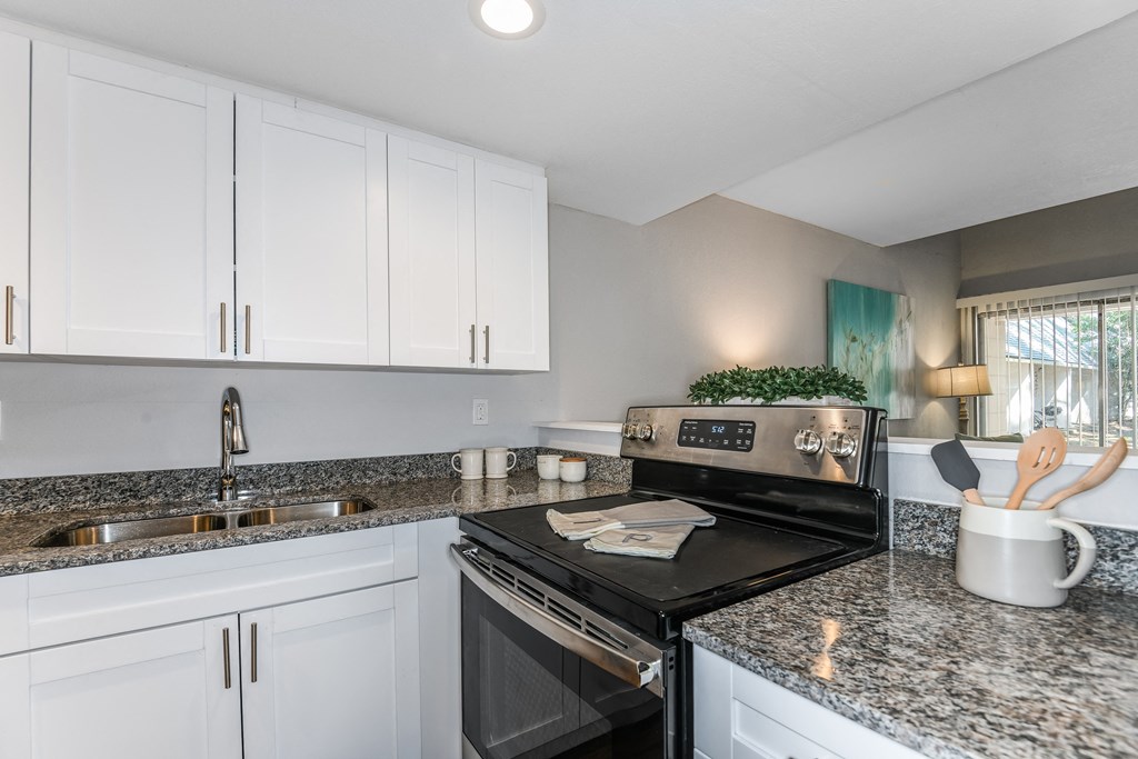 an updated kitchen with granite counter tops and black appliances