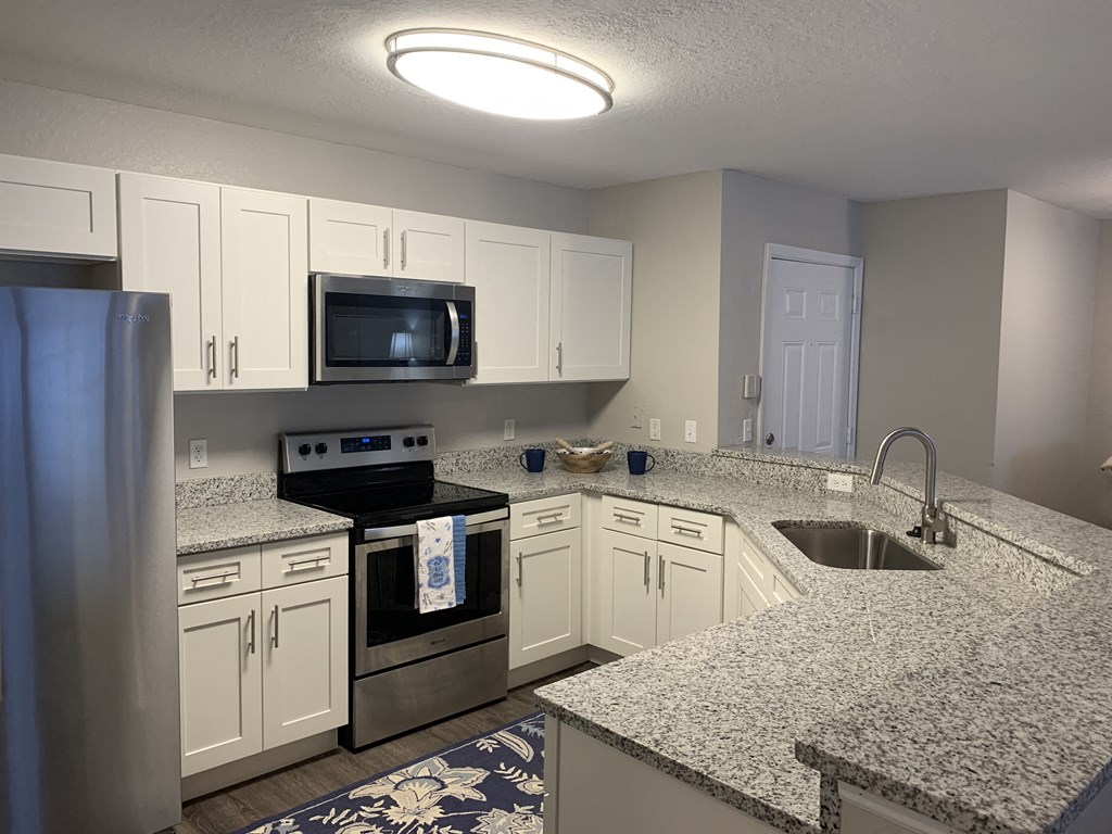 Compass kitchen with white cabinets and stainless steel appliances