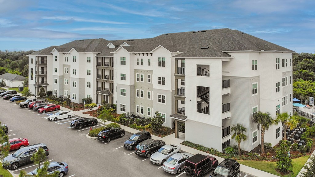 an aerial view of an apartment building with cars parked in the parking lot