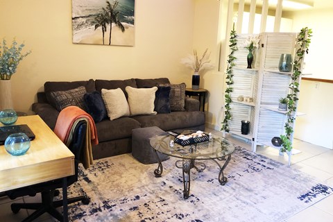 A living room with a couch, a table, and a painting on the wall.