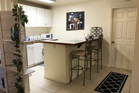 A kitchen with a white counter and bar stools.