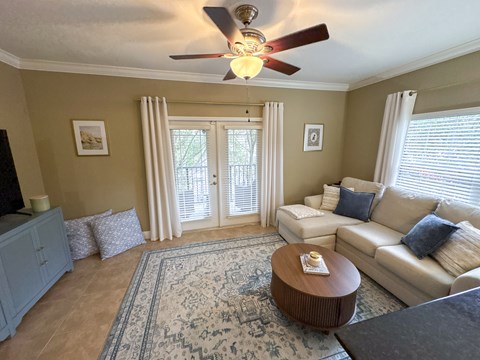A living room with a ceiling fan and a rug on the floor.