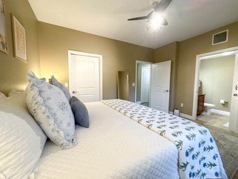 A bedroom with a large bed and a ceiling fan.