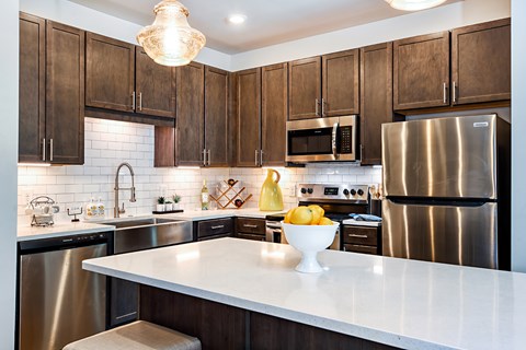 A modern kitchen with dark wood cabinets and stainless steel appliances.