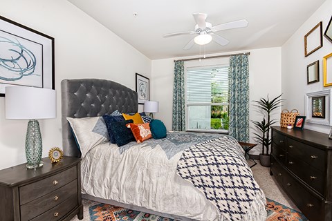 A bedroom with a bed, dresser, and ceiling fan.