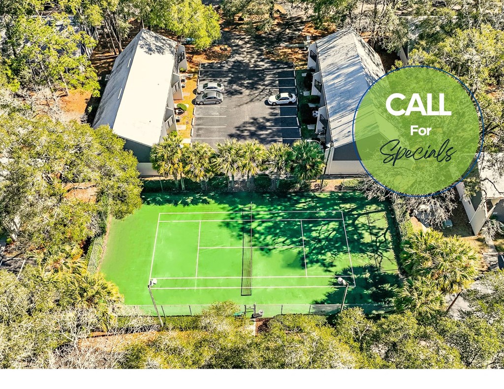 a house with a tennis court in the middle of a forest