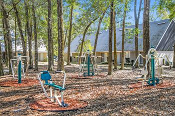 A park with exercise equipment and trees.
