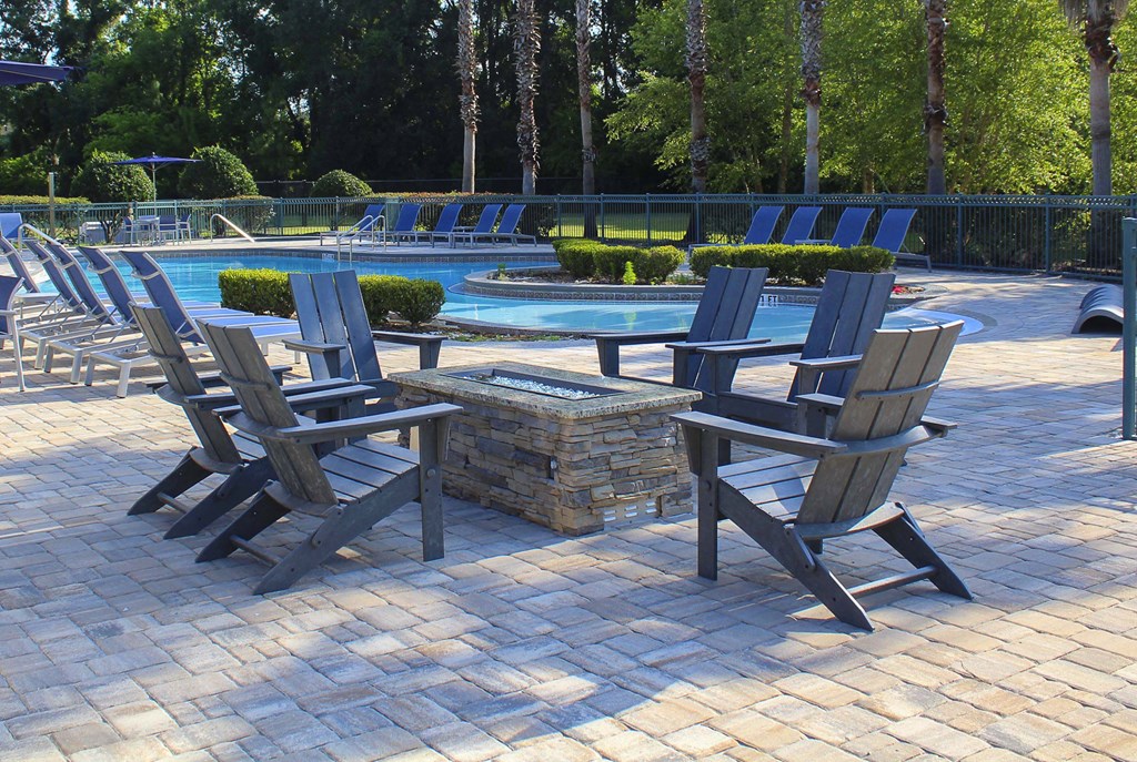 Gas fire pit with chairs and pool in background