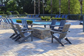 Gas fire pit with chairs and pool in background - Photo Gallery 6