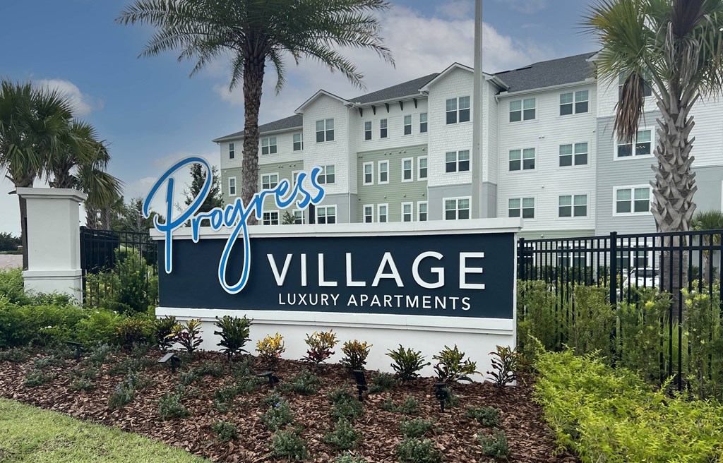 a large sign in front of an apartment building with palm trees