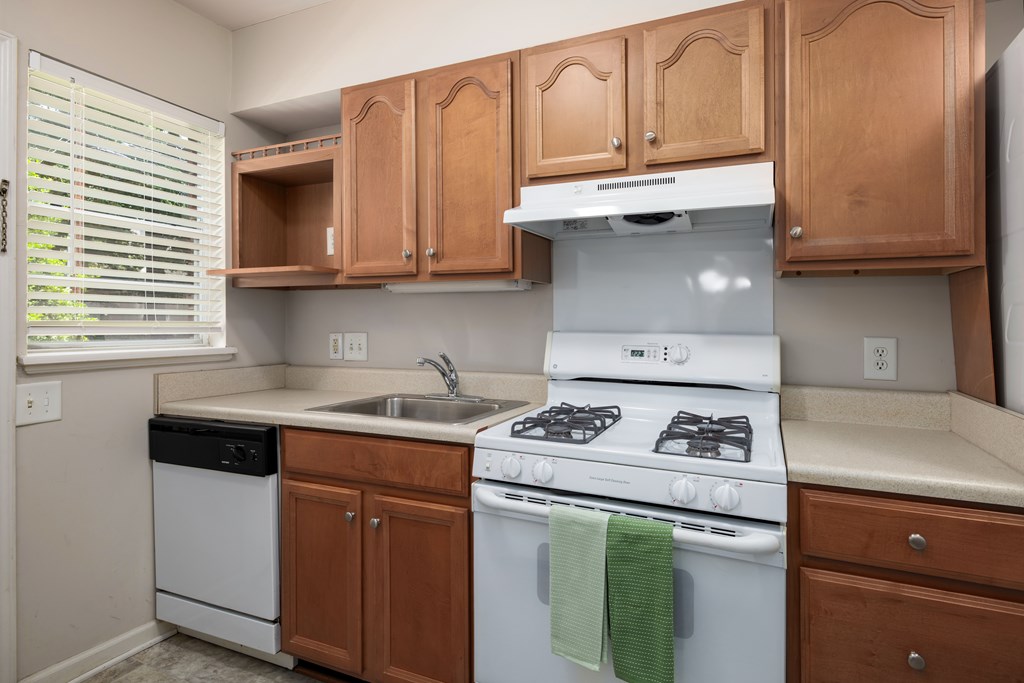 A kitchen with a white stove and wooden cabinets.