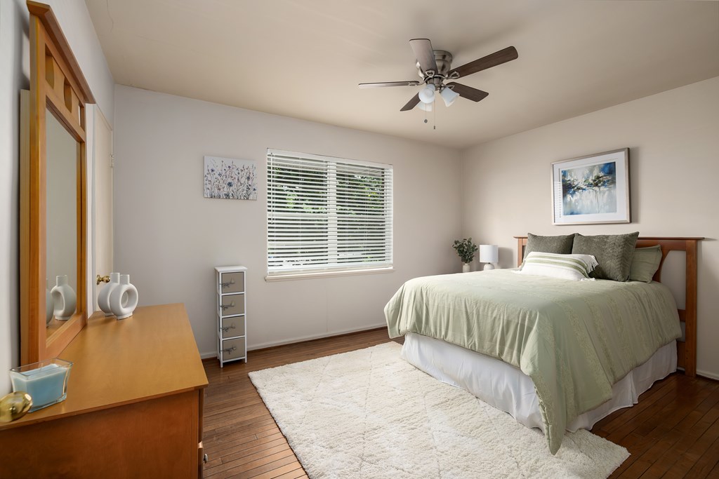 A bedroom with a bed, dresser, and window.