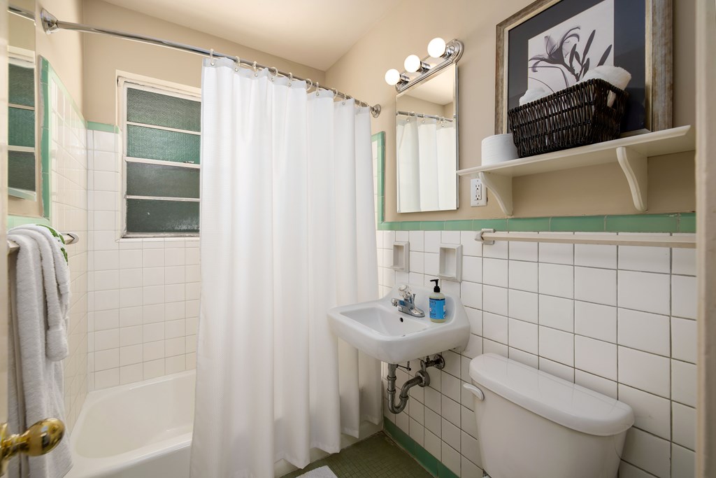 A bathroom with a white tub, sink, and toilet.