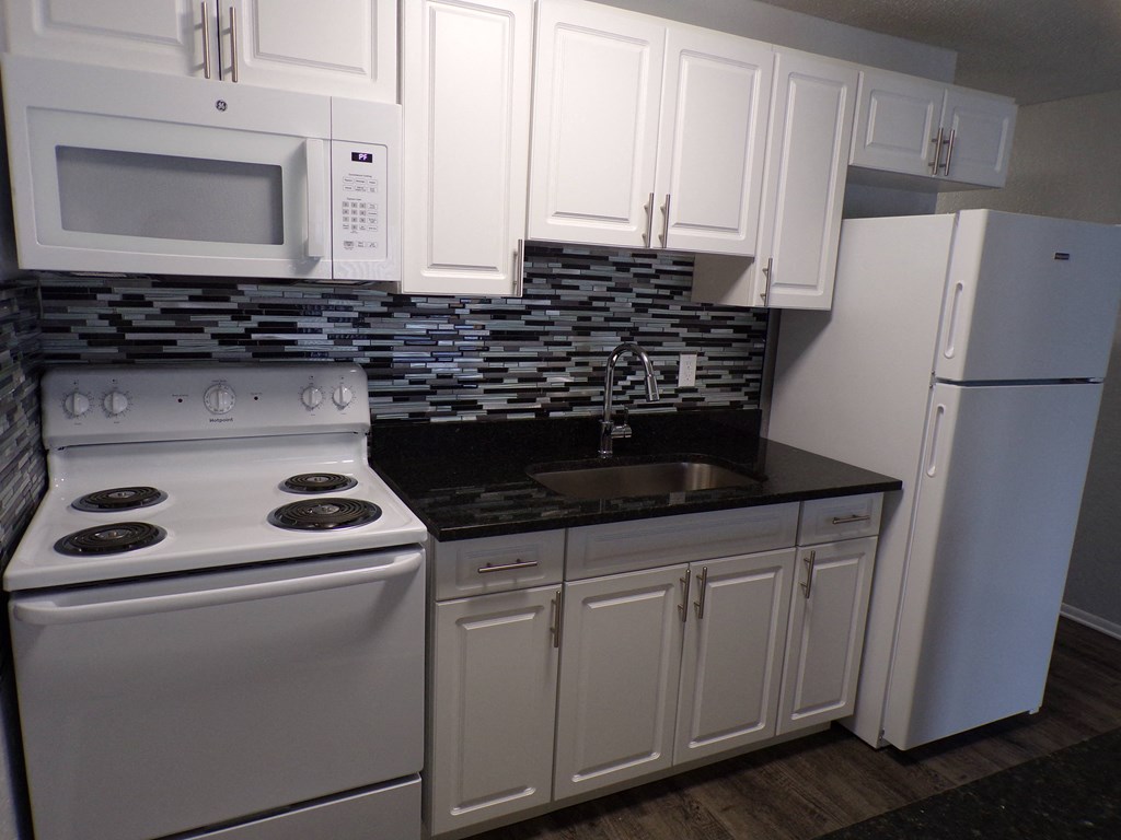 a kitchen with white appliances and white cabinets and a sink