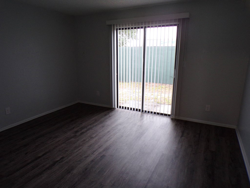 an empty living room with a sliding glass door to a balcony