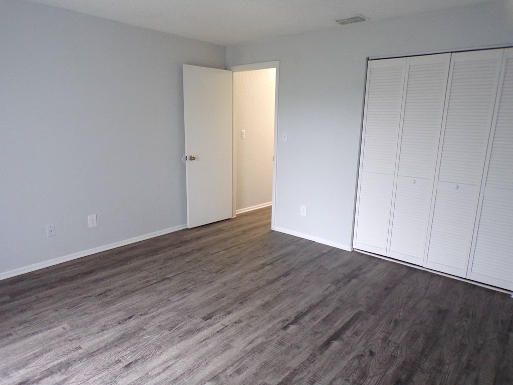 a bedroom with wood floors and white closets