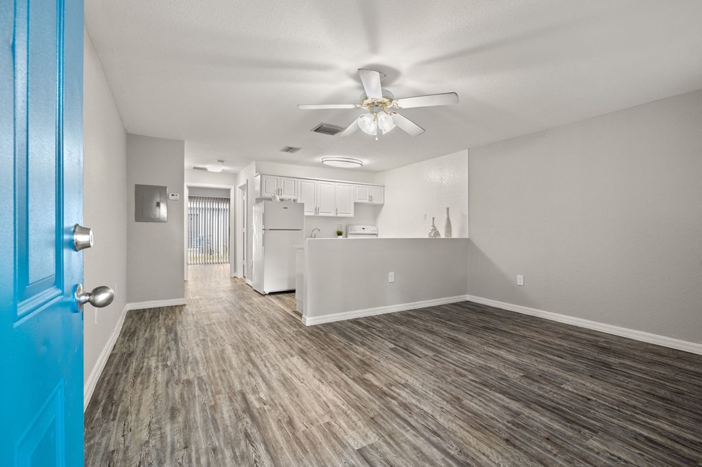 the living room and kitchen of an apartment with a blue door