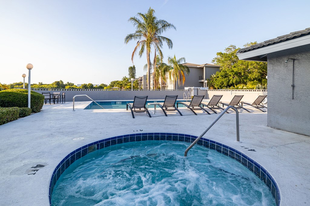 A hot tub with a blue tiled edge sits in the middle of a patio.