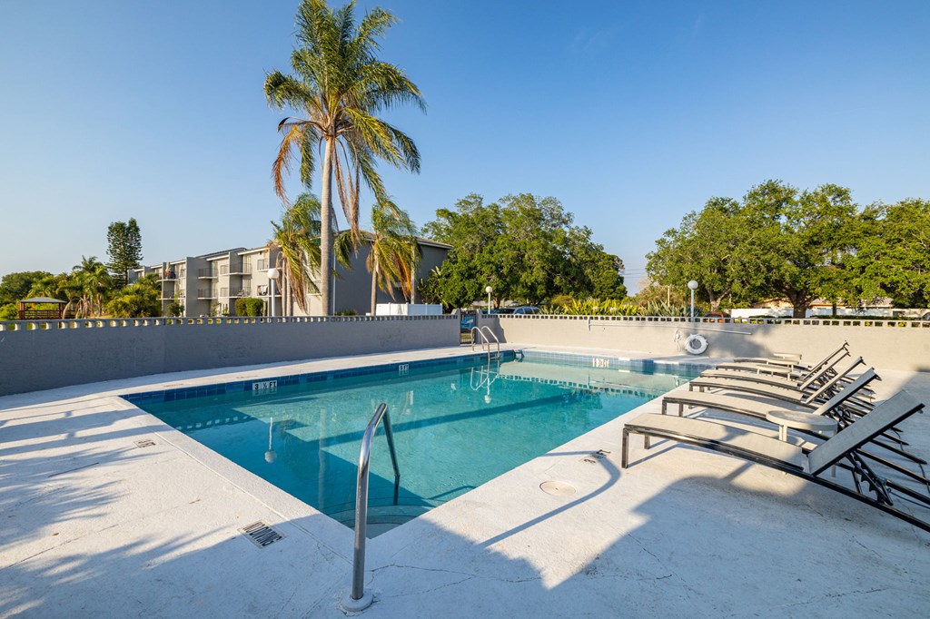 A pool with a diving board and sun loungers.