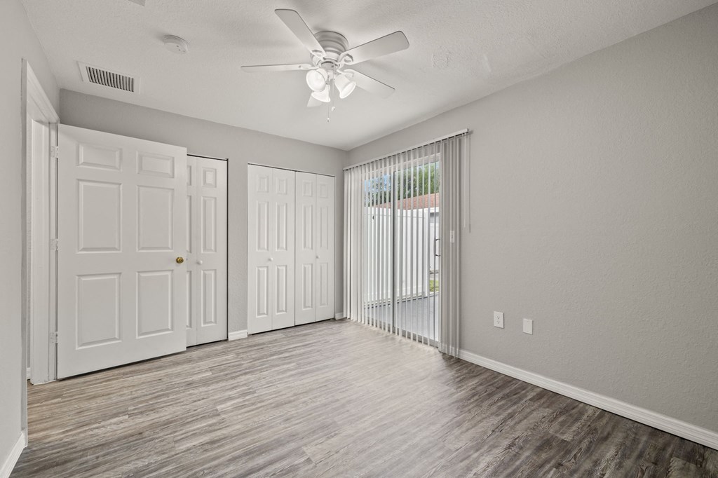 an empty living room with white doors and a ceiling fan
