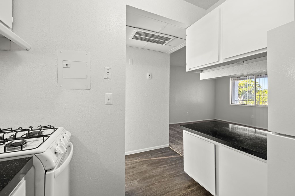 A kitchen with a stove, cabinets, and a window.