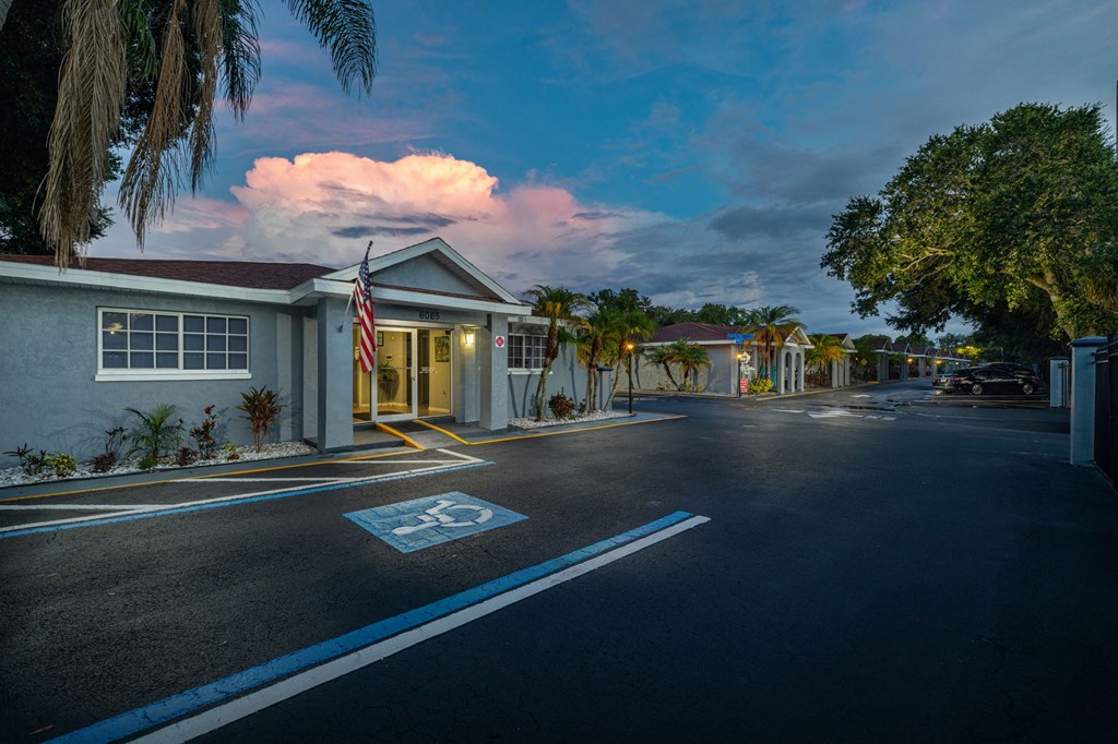 a street in front of a house with a flag and a cloudy sky
