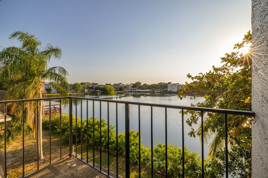 A balcony overlooks a body of water with a sunset in the background.
