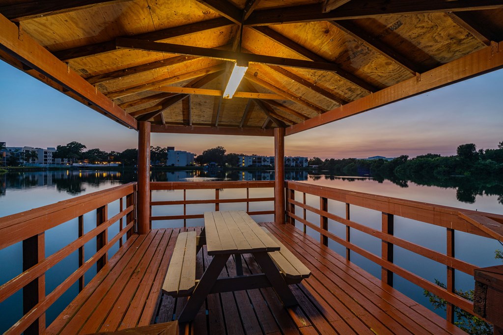 Picnic table on a wooden deck overlooking a body of water.