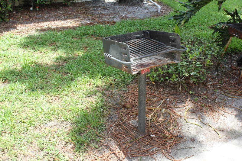 a barbecue grill on a pole in the grass