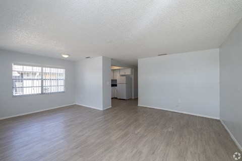 A spacious room with wooden flooring and white walls.
