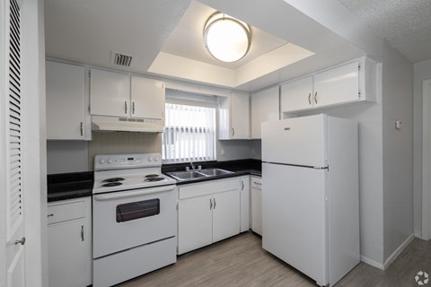 A white kitchen with a black countertop and stove.