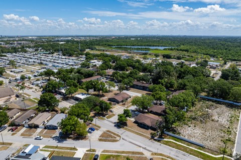 A bird's eye view of a residential area with houses, trees, and a parking lot.