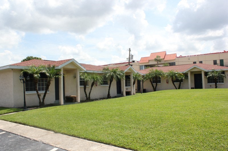 a lawn in front of a house with palm trees