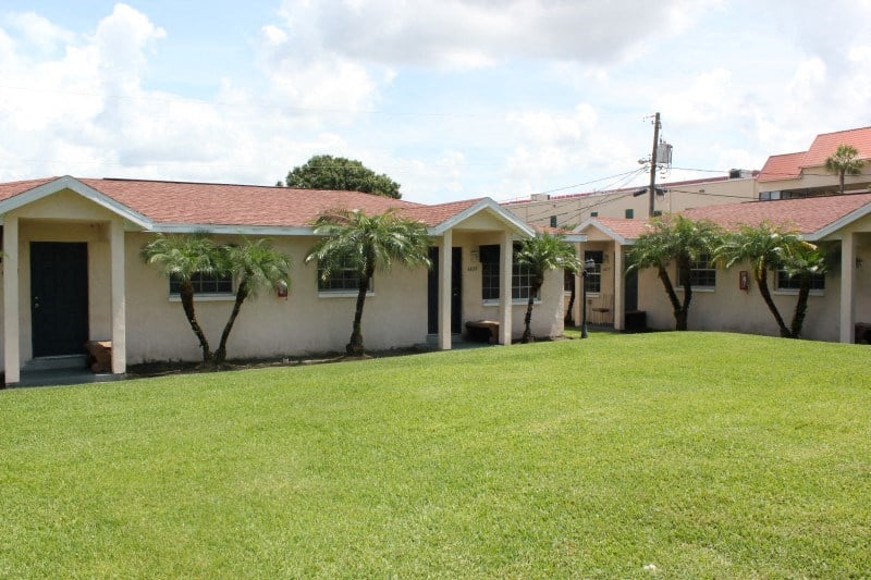 a house with a yard and palm trees in front of it