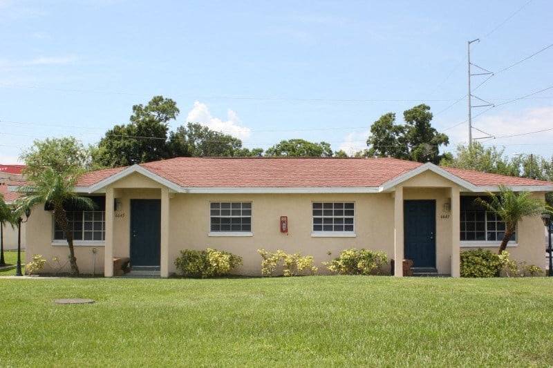 the front of a house with a grass yard and trees