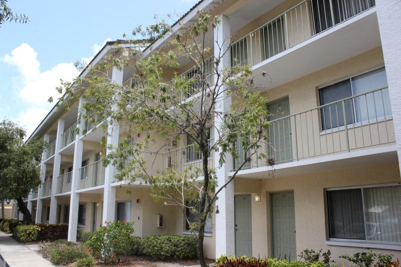 an apartment building with balconies and trees in front of it