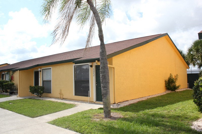 a yellow house with a palm tree in front of it