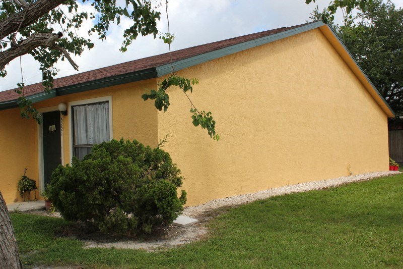 a yellow house with a green bush in front of it