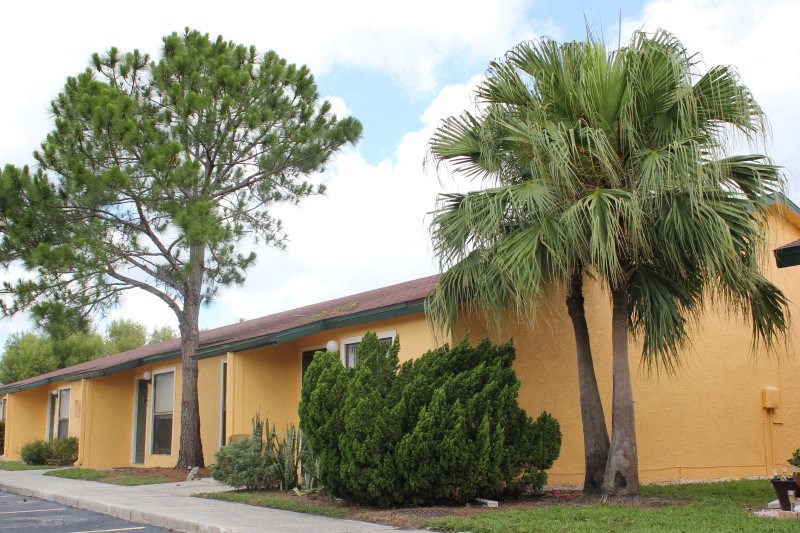 a yellow building with two palm trees in front of it