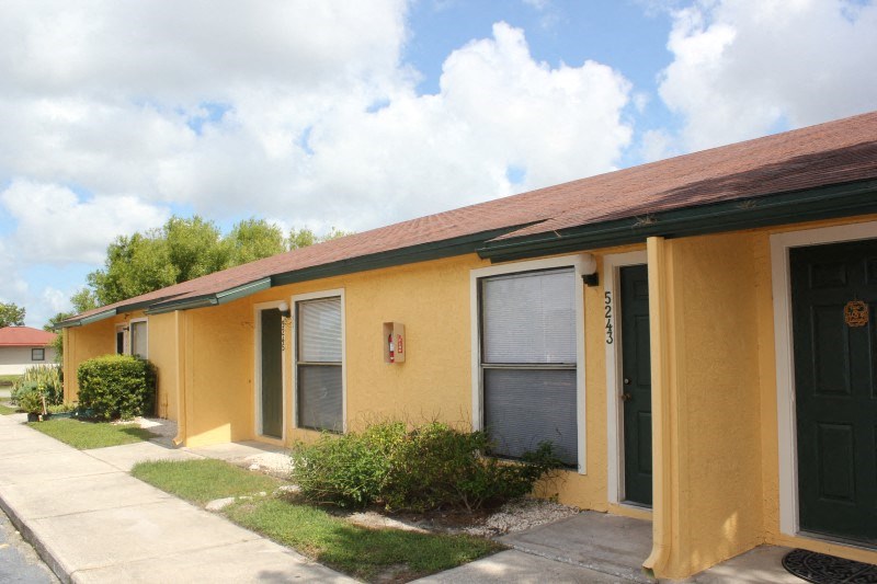 a yellow building with two windows and a sidewalk