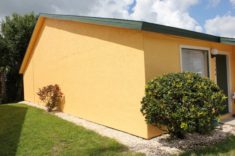 a yellow house with a lawn and bushes in front of it