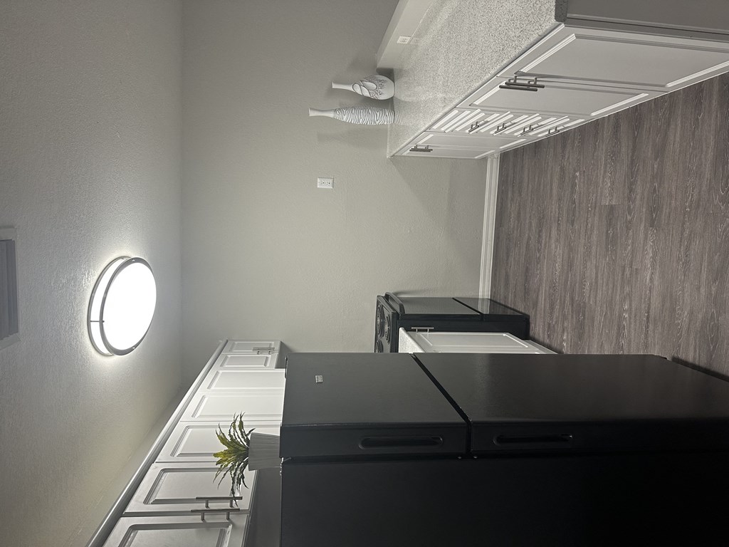 a kitchen with a black counter top and a light on the wall