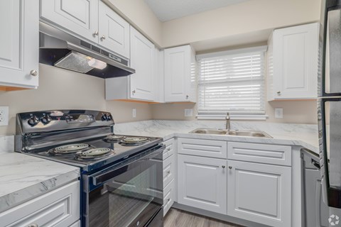A kitchen with white cabinets and a black stove top.
