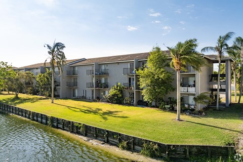 A row of apartment buildings with a body of water in front.