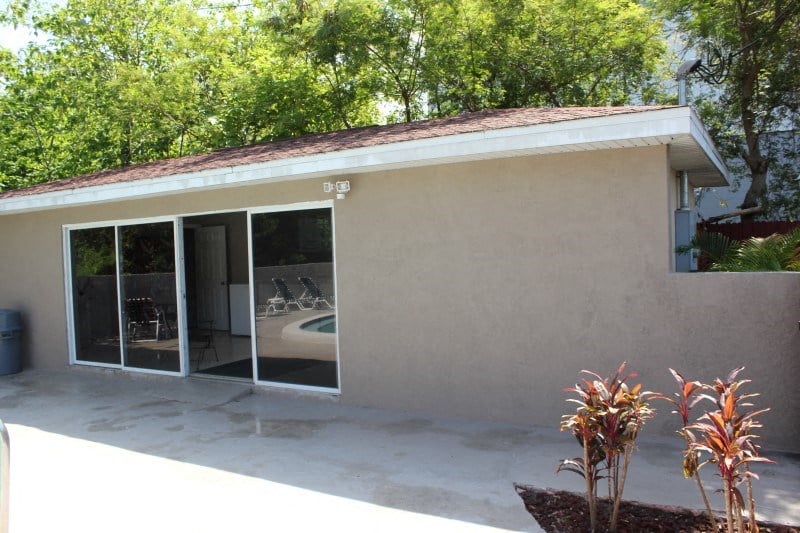 a house with a patio and sliding glass doors to a swimming pool