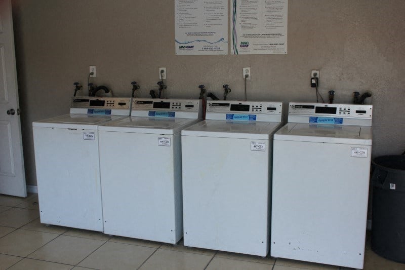 four washing machines are lined up against a wall