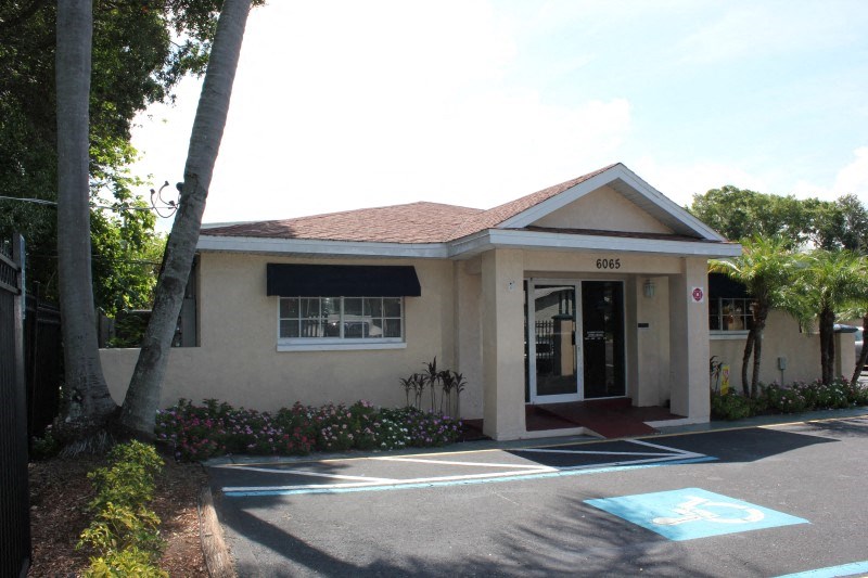 the front entrance of a cream colored building with a blue handicapped parking lot
