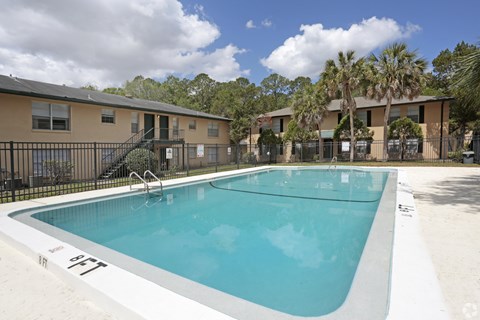 A swimming pool in a residential area with apartment buildings in the background.