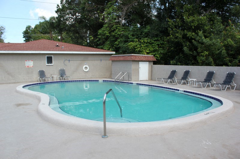 a swimming pool with chairs around it in front of a building