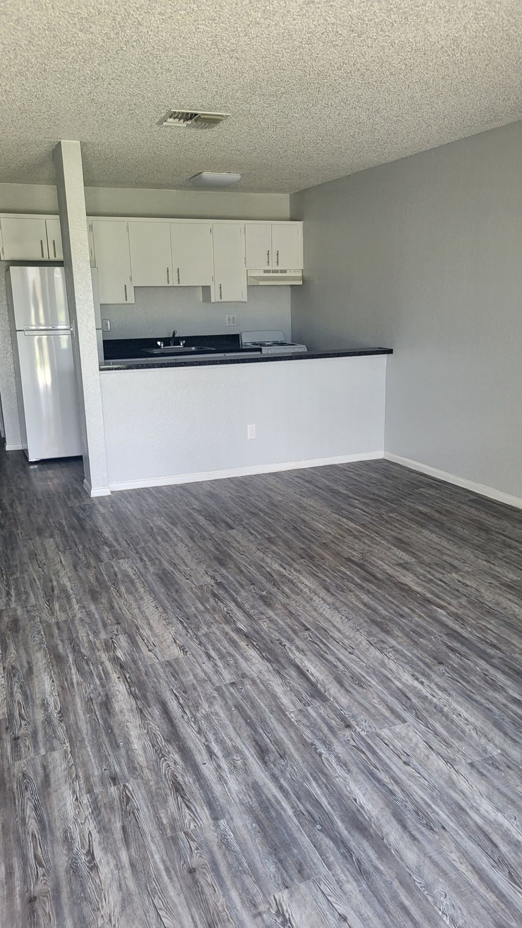 A kitchen with a white counter and a grey floor.